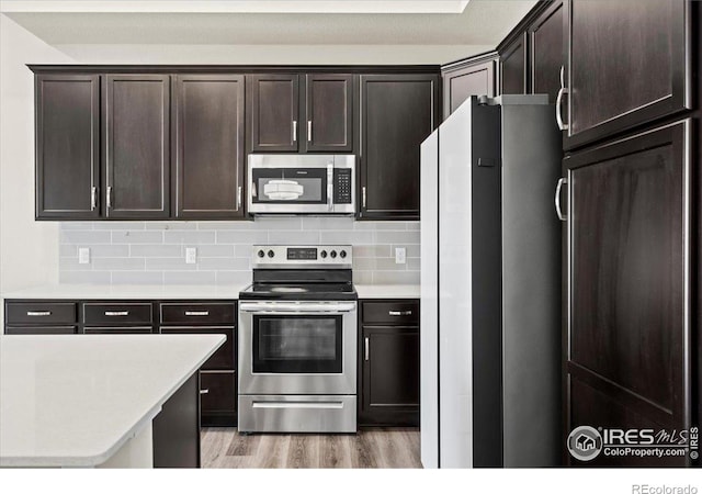350 High Point Dr Unit 201, Longmont, CO 80504 - kitchen featuring stainless steel appliances, light wood-type flooring, light countertops, decorative backsplash, and dark brown cabinetry