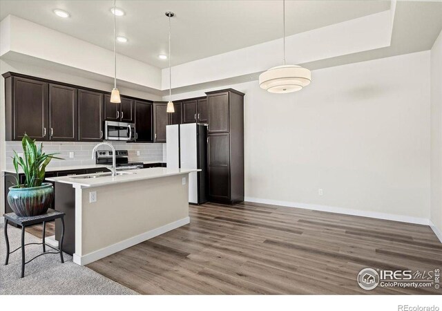 350 High Point Dr Unit 201, Longmont, CO 80504 - kitchen with appliances with stainless steel finishes, dark brown cabinetry, light wood-style flooring, light countertops, and backsplash