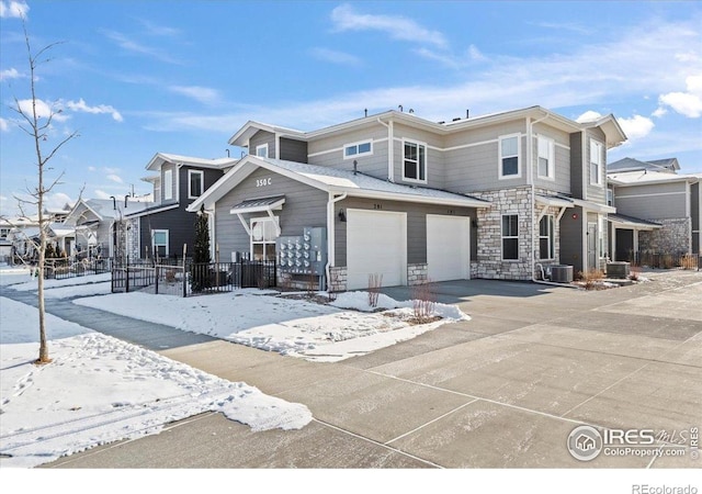 350 High Point Dr Unit 201, Longmont, CO 80504 - view of front of home with a garage, fence, central air condition unit, concrete driveway, and stone siding