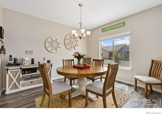 dining space featuring a chandelier, wood finished floors, and baseboards