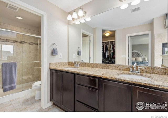 ensuite bathroom featuring toilet, a stall shower, double vanity, tile patterned floors, and a spacious closet