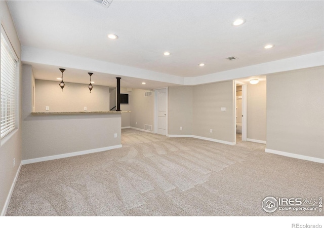 unfurnished living room featuring light colored carpet, recessed lighting, baseboards, and bar area
