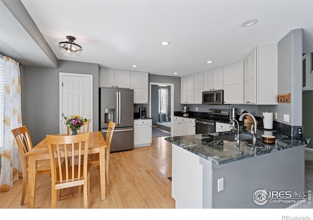 4416 Pika Dr, Loveland, CO 80537 - kitchen featuring appliances with stainless steel finishes, light wood-type flooring, white cabinetry, dark stone countertops, and recessed lighting