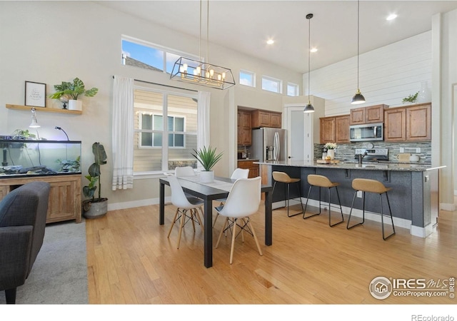 2119 Pelican Farm Rd, Windsor, CO 80550 - dining room featuring light wood-style floors, a towering ceiling, baseboards, recessed lighting, and a chandelier
