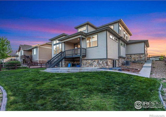 2119 Pelican Farm Rd, Windsor, CO 80550 - back of property at dusk with stone siding, stairway, central air condition unit, and covered porch
