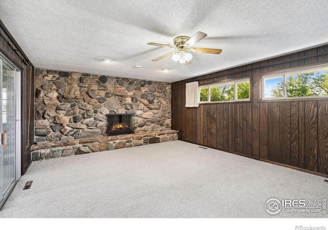 1320 Lory St, Fort Collins, CO 80524 - unfurnished living room with carpet, a ceiling fan, a textured ceiling, a fireplace, and wood walls