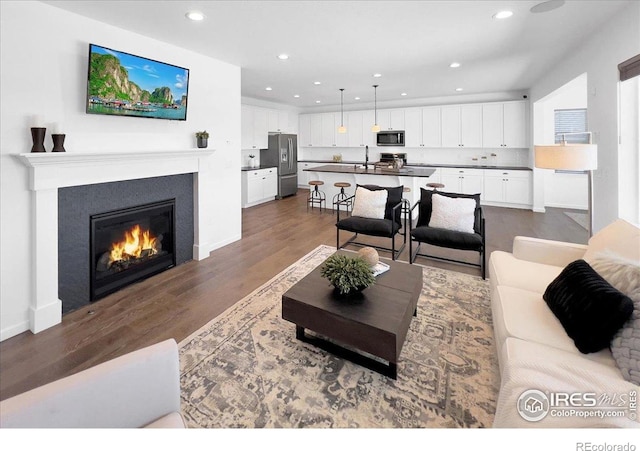 6506 Merrimack Dr, Castle Pines, CO 80108 - living area with dark wood-style floors, recessed lighting, a glass covered fireplace, and baseboards