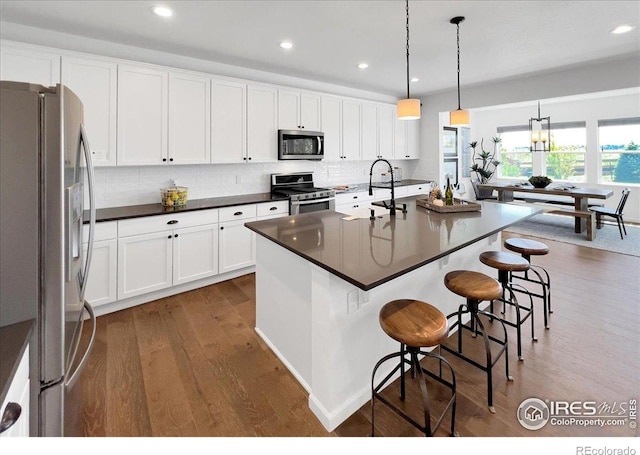 6506 Merrimack Dr, Castle Pines, CO 80108 - kitchen featuring appliances with stainless steel finishes, a sink, dark countertops, wood finished floors, and healthy amount of natural light