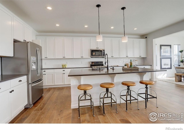 6506 Merrimack Dr, Castle Pines, CO 80108 - kitchen with stainless steel appliances, dark countertops, decorative backsplash, light wood finished floors, and recessed lighting