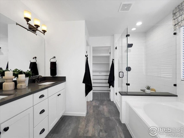 6506 Merrimack Dr, Castle Pines, CO 80108 - bathroom featuring wood finished floors, a stall shower, vanity, a garden tub, and baseboards