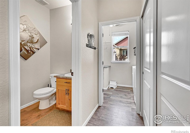 711 Mt Evans Ave, Severance, CO 80550 - bathroom with wood-type flooring, toilet, vanity, and baseboards