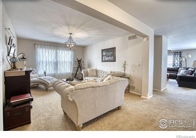 living area featuring carpet flooring, a chandelier, and baseboards