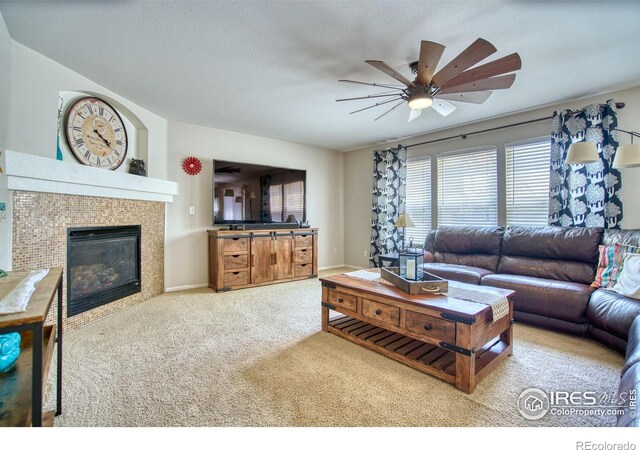 living area with ceiling fan, carpet floors, and a tile fireplace