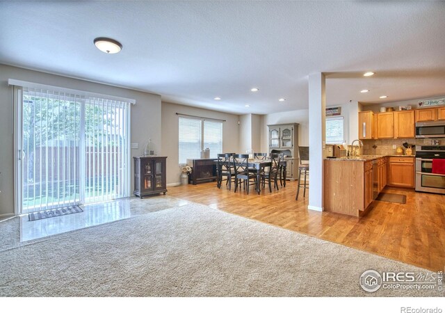 kitchen featuring appliances with stainless steel finishes, light colored carpet, recessed lighting, backsplash, and baseboards
