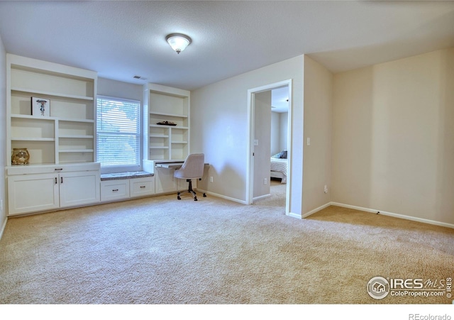 spare room featuring light colored carpet, baseboards, and a textured ceiling