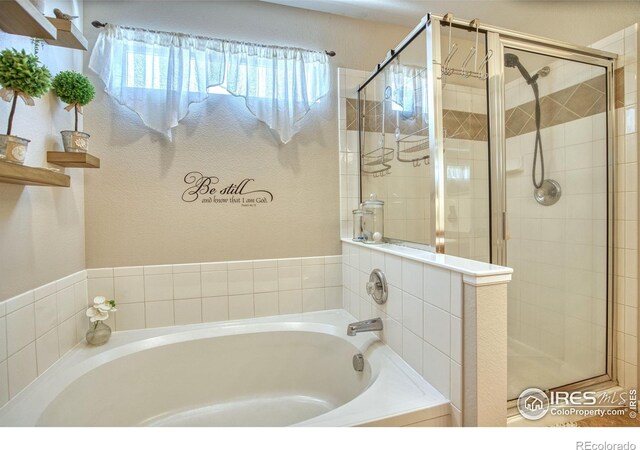 bathroom with a stall shower and a garden tub