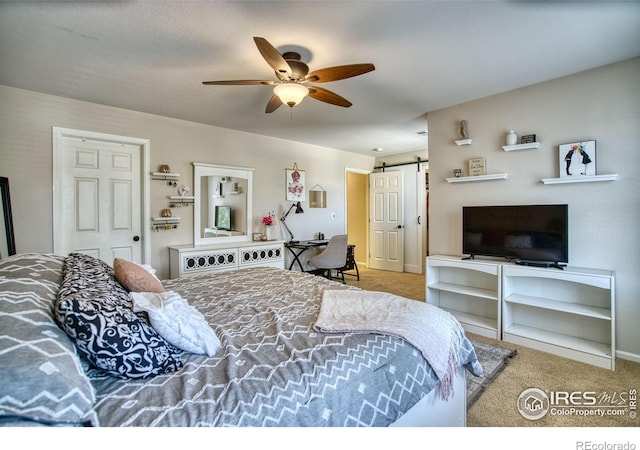 bedroom with a barn door, carpet, and a ceiling fan