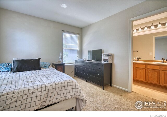 bedroom with a sink, light colored carpet, connected bathroom, and baseboards