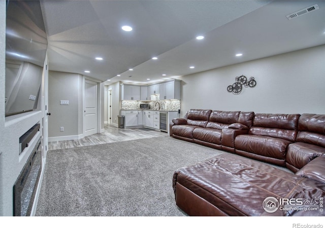 living room with beverage cooler, recessed lighting, light wood-style floors, baseboards, and bar