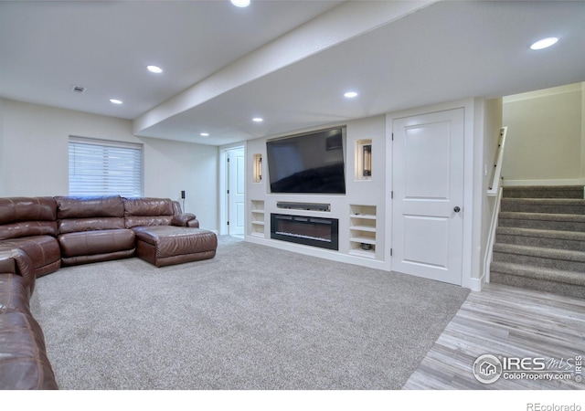living area with recessed lighting, stairs, wood finished floors, a glass covered fireplace, and baseboards