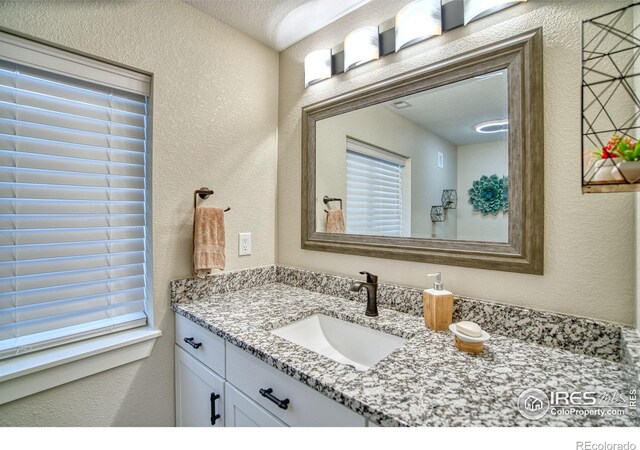 bathroom with a textured wall and vanity