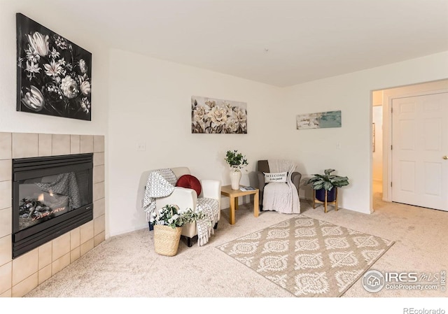 living area with carpet floors and a tiled fireplace
