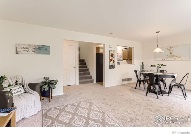 carpeted dining area with stairway and baseboards
