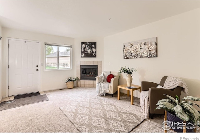 living room with carpet flooring, a tiled fireplace, and baseboards