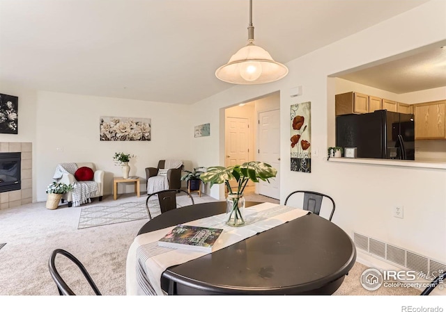 dining room featuring carpet and a tile fireplace