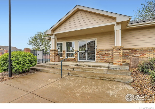 doorway to property featuring brick siding and a porch