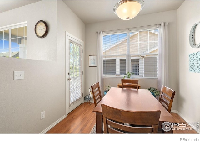 dining space featuring light wood-type flooring and baseboards