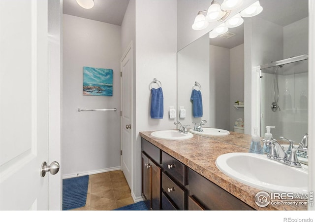 bathroom with a shower stall, baseboards, double vanity, and tile patterned floors