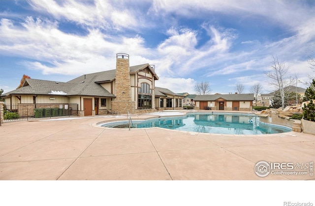 community pool with a patio area and fence