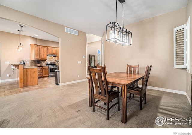 4609 Freehold Dr, Windsor, CO 80550 - dining area with light carpet, a chandelier, and arched walkways