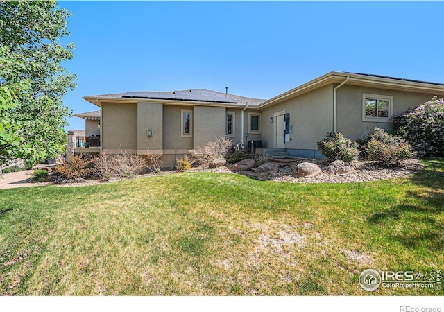 4609 Freehold Dr, Windsor, CO 80550 - back of house with stucco siding, roof mounted solar panels, and a lawn
