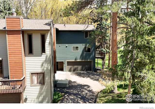 4888 Silver Spruce Ln, Evergreen, CO 80439 - back of property featuring an attached garage, driveway, central air condition unit, a chimney, and roof with shingles
