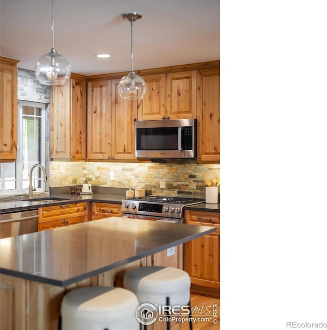 4760 Lee Cir, Boulder, CO 80303 - kitchen featuring appliances with stainless steel finishes, a sink, dark countertops, a breakfast bar, and backsplash