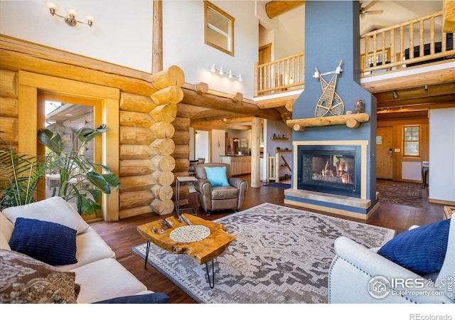 351 County Road 128n, Nederland, CO 80466 - living room with a high ceiling, rustic walls, a glass covered fireplace, ceiling fan, and wood finished floors