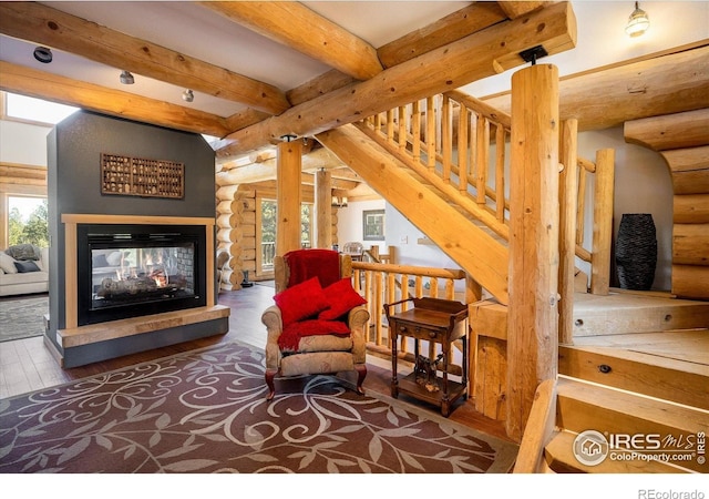 351 County Road 128n, Nederland, CO 80466 - living area featuring log walls, healthy amount of natural light, hardwood / wood-style flooring, beam ceiling, and a multi sided fireplace