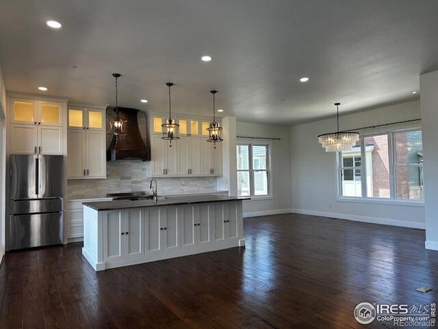 410 Superior Dr, Superior, CO 80027 - kitchen featuring freestanding refrigerator, custom exhaust hood, a chandelier, baseboards, and white cabinets
