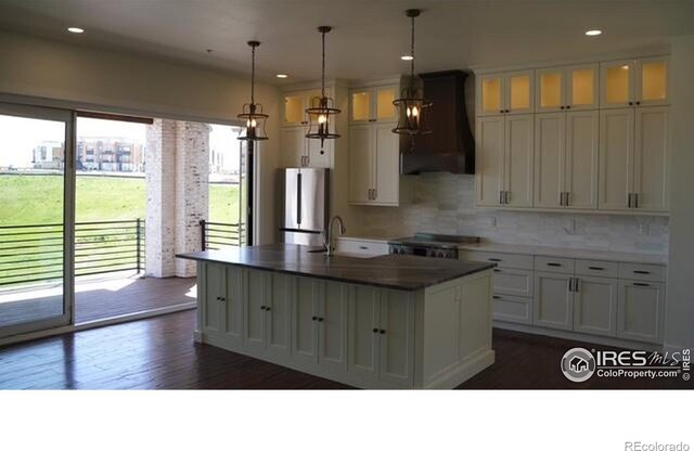 410 Superior Dr, Superior, CO 80027 - kitchen with freestanding refrigerator, premium range hood, dark wood-type flooring, a sink, and white cabinets