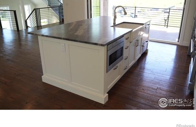 410 Superior Dr, Superior, CO 80027 - kitchen with stainless steel microwave, dark wood-type flooring, a sink, white cabinets, and dark countertops