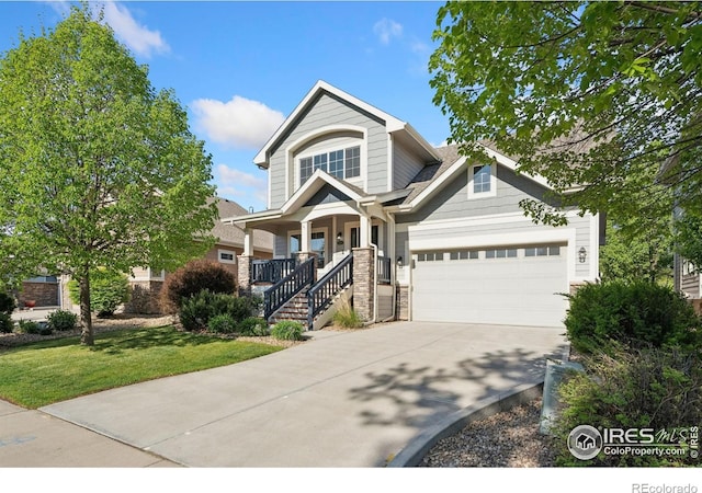 4045 Stoney Creek Dr, Fort Collins, CO 80525 - view of front facade featuring covered porch, driveway, an attached garage, a front lawn, and stone siding