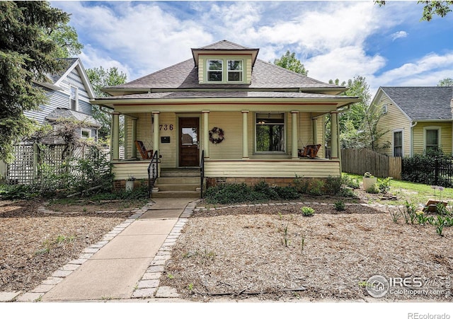 bungalow featuring fence, covered porch, and a shingled roof