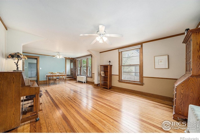 unfurnished living room with ceiling fan, light wood-type flooring, radiator, crown molding, and baseboards