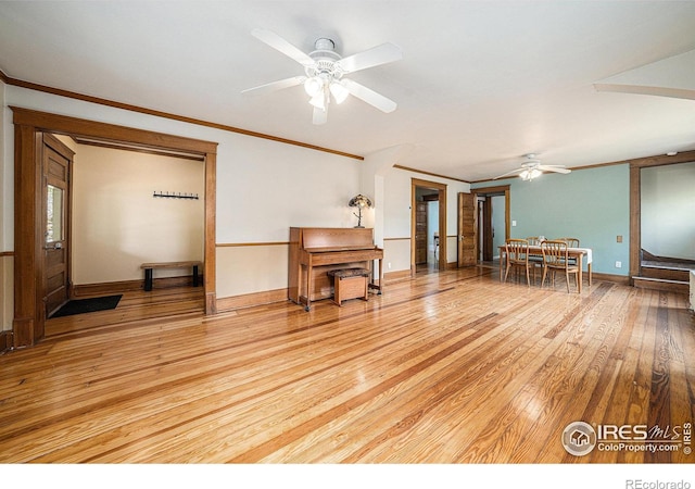 living room with ceiling fan, light wood finished floors, crown molding, and baseboards