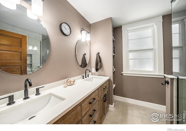 bathroom featuring tile patterned flooring, double vanity, an enclosed shower, and baseboards