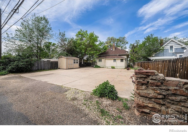fenced backyard with a shed, an outdoor structure, and a patio area