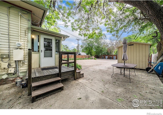 view of patio / terrace with fence, a shed, and an outbuilding