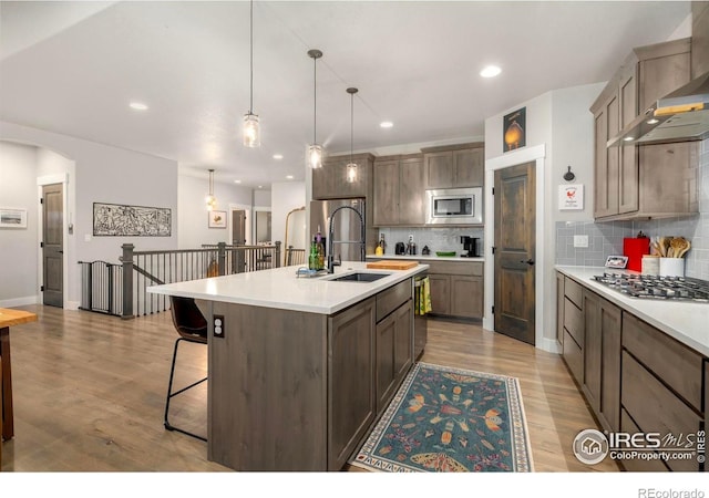kitchen featuring a sink, stainless steel appliances, wall chimney exhaust hood, tasteful backsplash, and recessed lighting